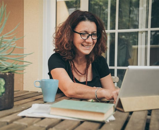 Connections Academy teacher in a black t shirt working at her laptop smiling 