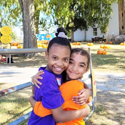 2 students at Missouri Connections Academy hug each other at a pumpkin patch on a fall day during a Connections Academy field trip.