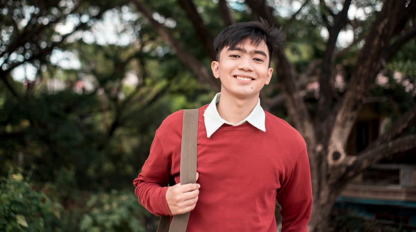 A Connections Academy. student standing outside with a bag over his shoulder