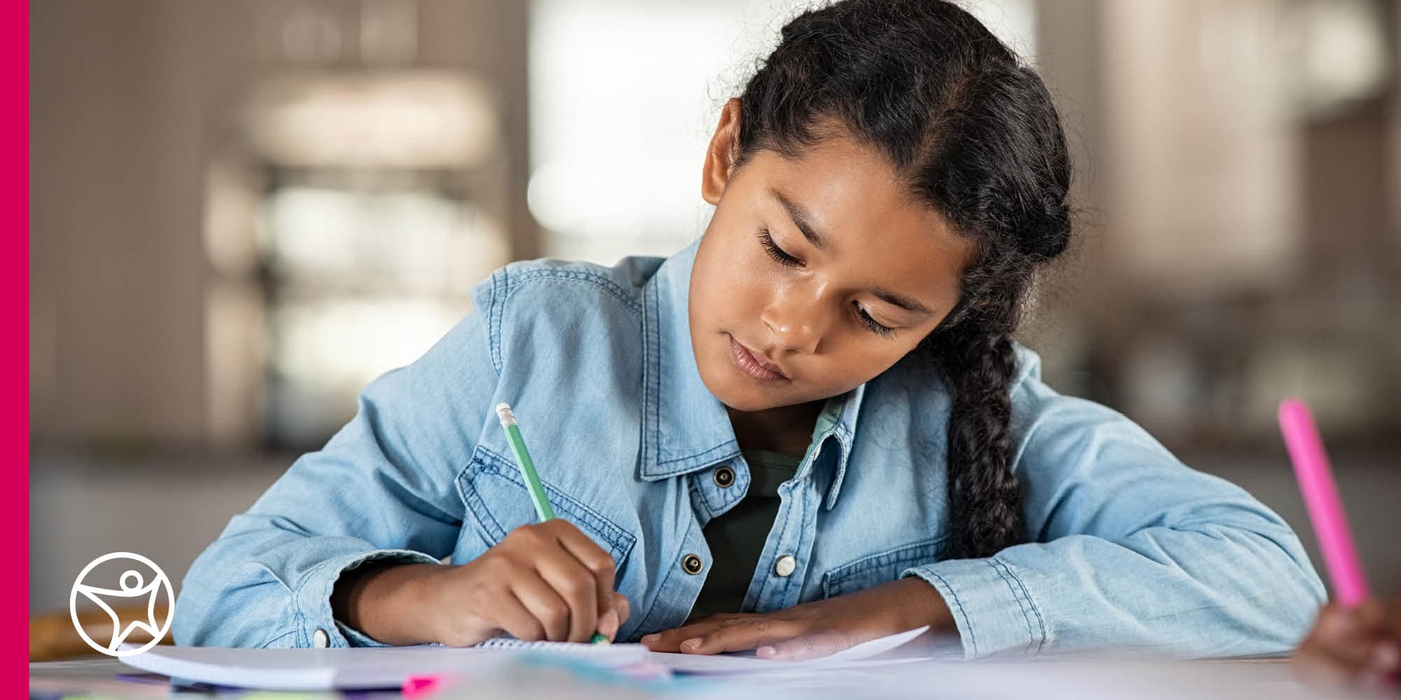 Connections Academy student in a blue denim shirt writing in her notebook