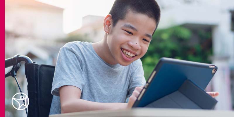 A student sitting in a wheelchair and using a tablet