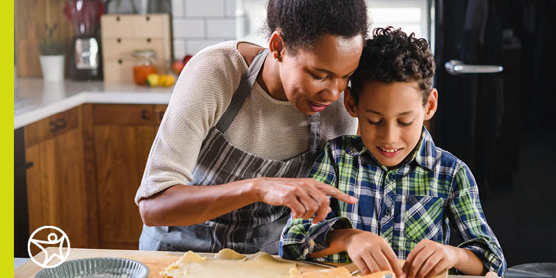 Mom and son making sugar cookies in the kitchen during the Christmas holiday.